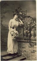 Woman with dress and flowers standing at a wall